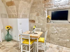 a dining room with a table and chairs and a tv at Antica Pietra in Polignano a Mare