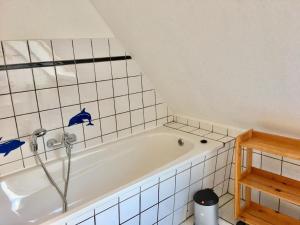 eine weiße Badewanne in einem weiß gefliesten Bad in der Unterkunft Ferienhaus "Oste-Anker" mit Sauna, Kaminofen und viel Platz für die Familie in ruhiger Lage in Oberndorf