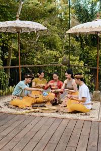 a group of people sitting on a rug under an umbrella at Vije Boutique Resort & Spa in Ubud +86 photos