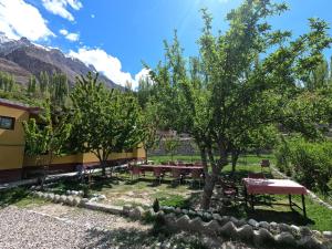 a garden with tables and trees and mountains in the background at Shaheen Resort Hunza-SRH in Hunza Valley