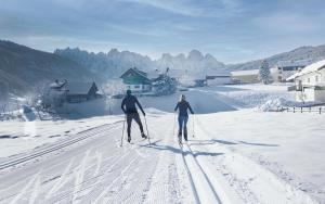 zwei Menschen Langlaufen im Schnee in der Unterkunft COOEE alpin Hotel Dachstein in Gosau