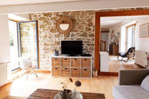 a living room with a tv on a stone wall at Ty Glaz Lilia - La maison bleue in Plouguerneau