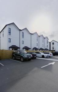 a parking lot with cars parked in front of a building at Modern Townhouse, Prime Location, Carpark in Christchurch