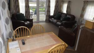 a living room with a couch and a table and chairs at Modern 3 bedroom lodge at Avonvale Holiday Lodges in Evesham +13 photos