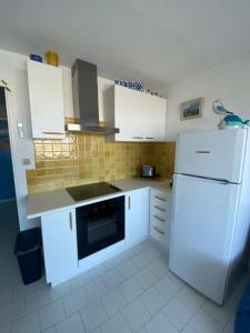 eine Küche mit weißen Schränken und einem weißen Kühlschrank in der Unterkunft Softness of the shore on the port side in Frontignan
