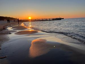 a sunset on a beach with a pier at LIKE APARTMENT in Kołobrzeg