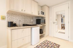 a kitchen with white cabinets and a microwave at Charmoso Flat na Serra - Granja Brasil Itaipava in Itaipava