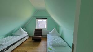 een zolderkamer met 2 bedden en een stoel bij Ferienhaus Heimathafen Dranske in Dranske
