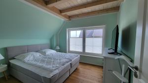 een slaapkamer met een bed en een flatscreen-tv bij Ferienhaus Heimathafen Dranske in Dranske