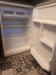 an empty refrigerator with its door open in a kitchen at Annexe indépendante in Bourron-Marlotte
