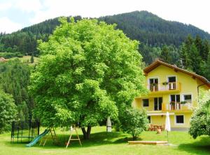 ein Baum mit einem Spielplatz vor einem Haus in der Unterkunft Kolarnock in Feld am See