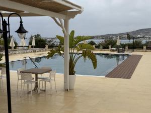 a patio with a table and chairs next to a pool at Vrachia Beach Hotel & Suites - Adults Only in Paphos