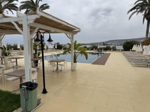 a patio with tables and chairs next to a pool at Vrachia Beach Hotel & Suites - Adults Only in Paphos