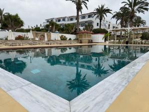 a swimming pool in front of a hotel with palm trees at Vrachia Beach Hotel & Suites - Adults Only in Paphos
