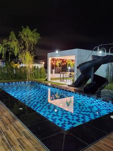 une piscine la nuit avec un toboggan dans l'établissement Morning Glory Pool Villa Chaam-Huahin, à Sathani Huai Sai Tai
