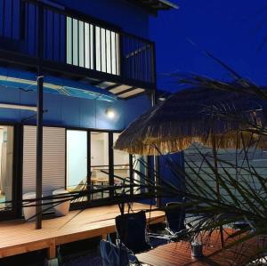 a building with a deck with chairs and an umbrella at 遊びの宿KONoさんち in Tateyama