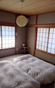a bedroom with a large white bed with windows at 遊びの宿KONoさんち in Tateyama