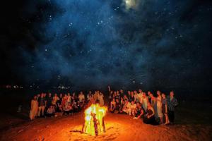 a group of people standing around a bonfire at night at Ho Tram Beach Boutique Resort & Spa in Ho Tram +139 photos