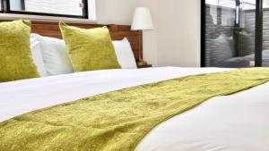 a bed with white sheets and yellow pillows at Antares Nago in Nago
