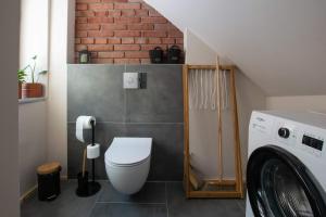 a small bathroom with a toilet and a washing machine at Kamienica Marianna in Reszel +15 photos