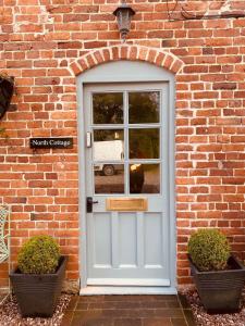 a white door on a brick building with two plants at North Cottage in Berriew