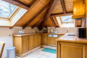 a kitchen with wooden cabinets and a roof with windows at Appt 4 pers-chalet l'ancienne école in La Bresse +18 photos
