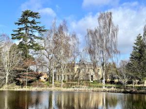 a large building in front of a lake with trees at North Cottage in Berriew