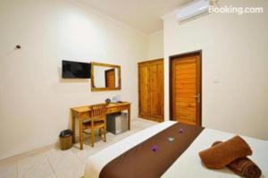 a bedroom with a bed and a desk and a television at Canggu Kayuma House in Canggu