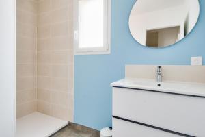 ein Badezimmer mit einem weißen Waschbecken und einem Spiegel in der Unterkunft Jolie maison pour 8 - 400m de la plage - terrasse in La Guérinière + 10 Fotos