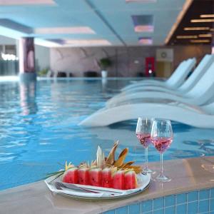due bicchieri di vino e un piatto di frutta accanto alla piscina di Wyndham Lynn Times Thanh Thuỷ a Xuân Vi
