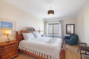 a bedroom with a large bed and a blue chair at Casa dos Salgados in Albufeira