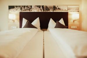 ein großes Bett mit weißer Bettwäsche und braunen Kissen in der Unterkunft Meyerhof - Weingut, Vinothek & Gästehaus in Flonheim