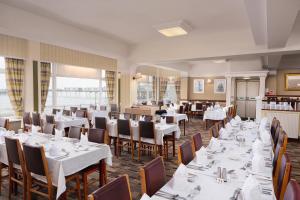 a dining room with white tables and chairs at Trouville Hotel by Compass Hospitality in Sandown
