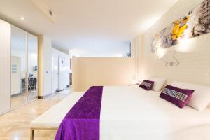 拉斯帕爾馬斯的住宿－畢加索花園閣樓公寓，卧室配有一张大白色床和紫色床单
