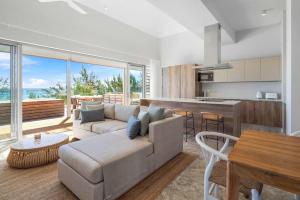 a living room with a couch and a kitchen at Aqua Serena - Luxury Beachfront Penthouse in Grand Gaube