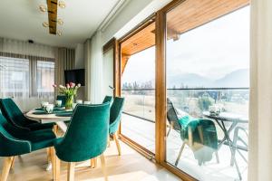 a dining room with a table and chairs and a balcony at Apartamenty Krokusowa Dolina in Kościelisko