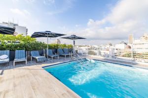 una piscina en la azotea de un edificio con sombrillas en Oceanfront Oasis 2-BR Apartment on Ocean Drive, en Miami Beach