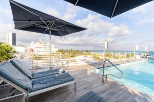 una piscina con una silla y una sombrilla en el balcón en Oceanfront Oasis 2-BR Apartment on Ocean Drive, en Miami Beach