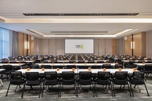a conference room with tables and chairs and a screen at Home2 Suite by Hilton Hengshui Taocheng in Hengshui