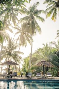 a pool with palm trees and chairs next to it at Isolabella Ayurveda Hotel Hiriketiya in Nilwella
