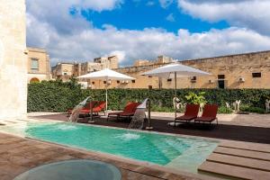 Palazzo Corte Dei Granai Raro Villas Homes Collection في ماليي: مسبح وكراسي ومظلات بجانب مبنى