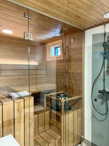 a sauna with wooden walls and a glass shower at Kotimaailma Apartments Patokuja in Kempele