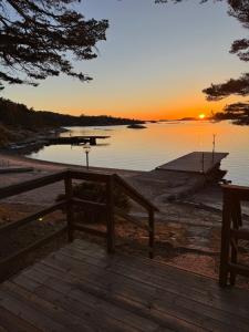 a boat on the shore of a lake at sunset at Hällestrand Cottage -Sillen in Strömstad