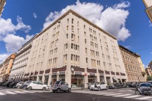 un grande edificio bianco con auto parcheggiate di fronte di Boezio 6 Rooms by Roman Dreams a Roma