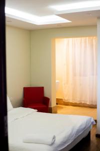 una habitación con dos camas y una silla roja en Tsiriry Guest House, en Antananarivo