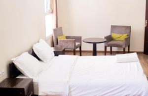 Un dormitorio con una cama y dos sillas y una mesa. en Tsiriry Guest House, en Antananarivo