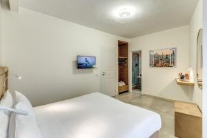 una camera da letto bianca con un letto e una TV di Boezio 6 Rooms by Roman Dreams a Roma