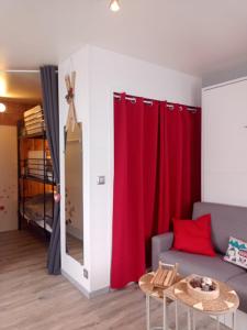 un soggiorno con tende rosse e un divano di Appartement hyper centre ville,5pers 'le maloudgja' vue sur le sancy a Le Mont-Dore Altre 41 foto