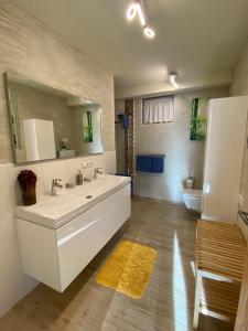 W łazience znajduje się duża, biała umywalka i lustro. w obiekcie Haus Zimba Ferienwohnung am Bartholomäberg w mieście Bartholomäberg