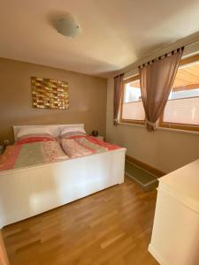 a bedroom with a white bed and a window at Haus Zimba Ferienwohnung am Bartholomäberg in Bartholomäberg